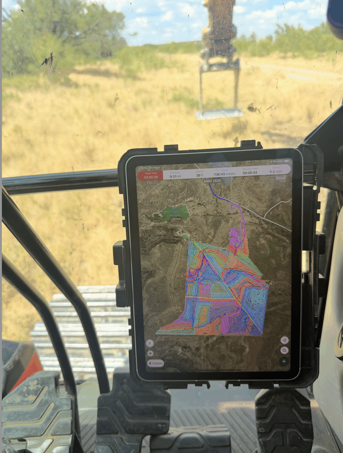 iPad mounted in an excavator cab showing the mapped grubbing plan and completed machine tracks.